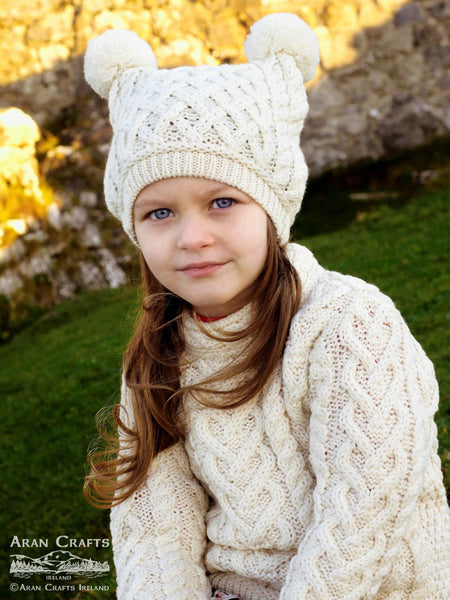 Children's Pom Pom Hat in Natural - 100% Merino Wool knitted Hat with two pom poms for children, on model