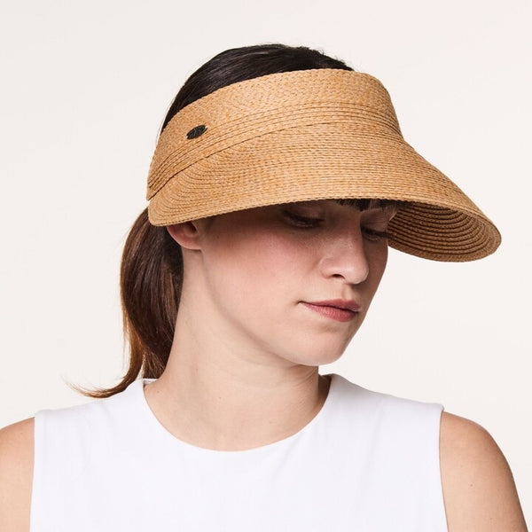 Woman wearing a tan Venicia visor on a white background.