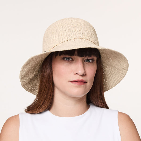 Woman wearing the Corinne fine paper straw crochet cloche hat in the natural colour.