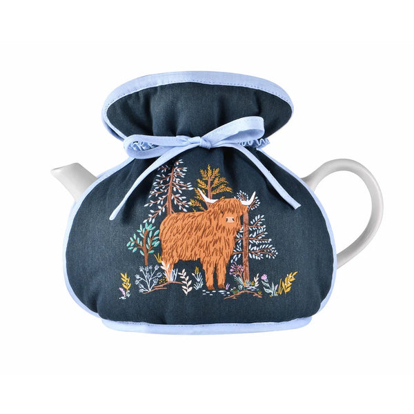 Connie the Cow Tea Cosy shown with a white teapot inside and on a white bacckground.