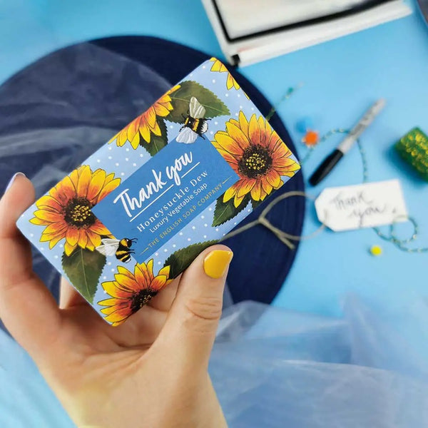 Hand holding a bar of soap beautifully wrapped with writing Thank you Honeysuckle Dew Luxury Vegetable Soap