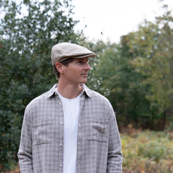 A male wearing the Irish linen flat cap with a forested landscape background.