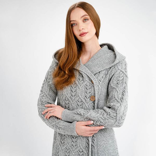 Woman wearing a gray cable knit coat on a white background