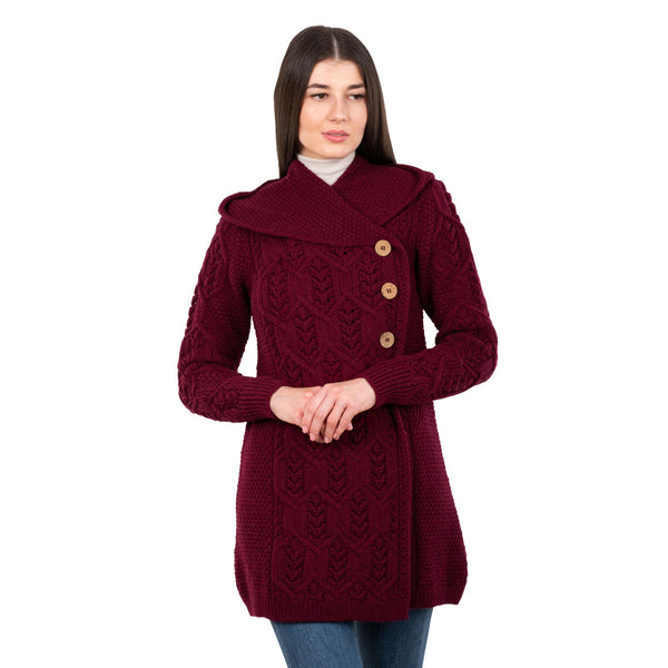 Woman wearing a wine coloured knitted coat with button details on a white background