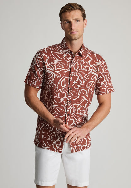 Male model wearing rust coloured floral cotton linen short sleeved shirt.