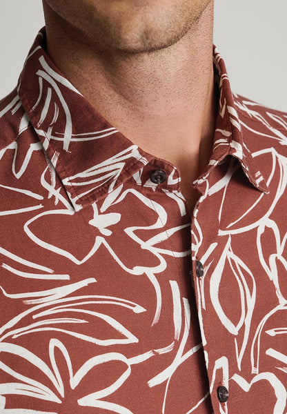 Male model wearing rust coloured floral cotton linen short sleeved shirt and an up close view of the neckline.