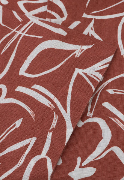 Up close view of the fabric and sleeve end of the rust coloured floral cotton linen short sleeved shirt.