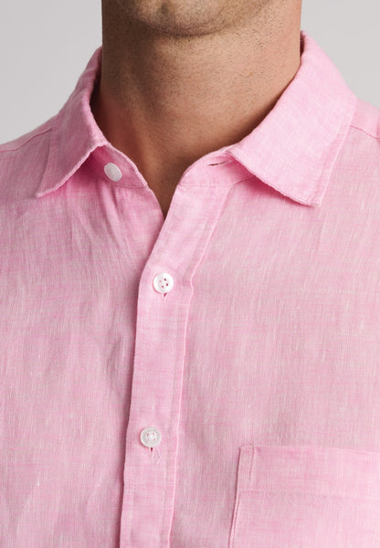 A man wearing a light pink linen short-sleeve button-down shirt, with close up of neckline