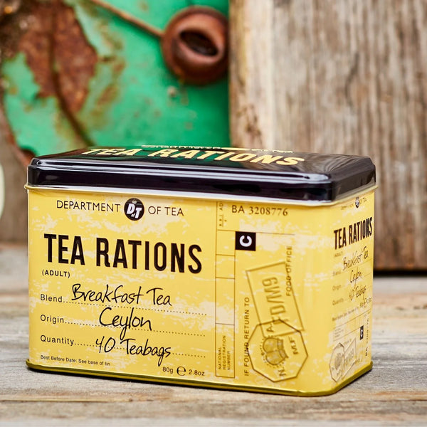 Yellow tea canister labeled 'Tea Rations' on a wooden surface with a rustic background.