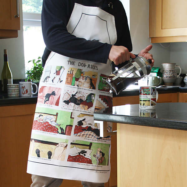 Person wearing a colorful apron with dog-themed designs in a kitchen.
