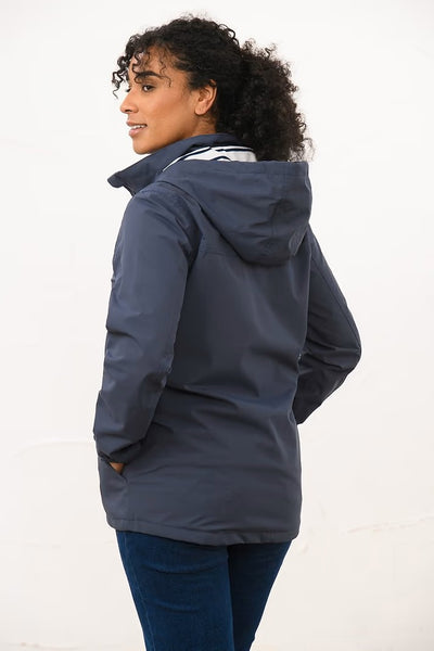 Woman wearing a navy hooded Lighthouse Beachcomber  jacket on a white background