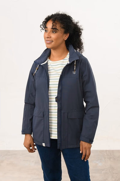 Woman wearing a navy blue Lighthouse Beachcomber jacket with a white background