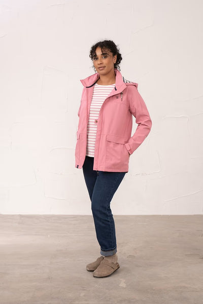 Woman wearing a pink Lighthouse Beachcomber coat standing against a white wall.