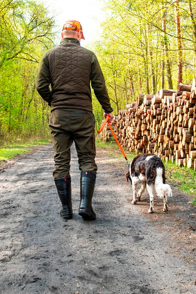 Picture showing a person walking on a trail with a dog, while the person wears the Highlander boots.